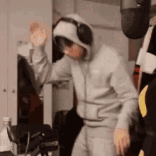 a man wearing headphones and a hoodie is standing in a room .
