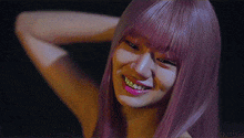 a woman with purple hair and pink lips is smiling and looking at the camera .