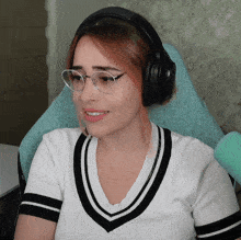 a woman wearing headphones and glasses smiles for the camera