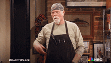 a man wearing an apron and a bandana stands in front of a wall with a picture of a fish on it