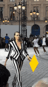 a woman in a black and white striped suit is walking down a street