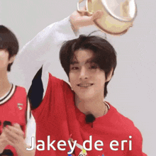 a young man in a red shirt is holding a tambourine in his hand and smiling .