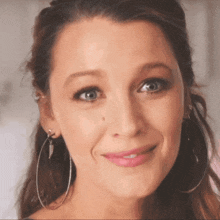 a close up of a woman wearing hoop earrings and smiling