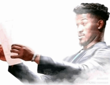 a man in a suit is holding a piece of paper in his hands
