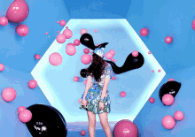 a woman in a blue dress is surrounded by pink balloons and black balloons