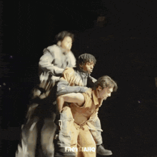 a man is carrying another man on his back on a stage in the dark .