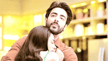 a man with a beard is hugging a woman with long brown hair .