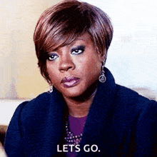 a woman is wearing a blue coat and earrings and says `` lets go '' .
