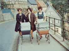 three women pushing stroller on a sidewalk in front of buildings