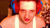 a shirtless man wearing red and blue headphones and a white tank top .