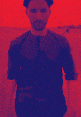 a man in a red and blue shirt stands in front of a red background