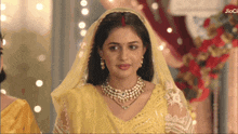 a woman in a yellow dress with a red bindi on her forehead stands in front of a sign that says jiocl