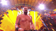 a man without a shirt is standing on a stage in front of a yellow background .