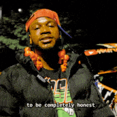 a man wearing a black jacket and an orange hat says " to be completely honest "