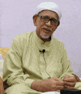 a man wearing glasses and a white headband has a microphone attached to his neck