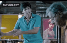 a man in a blue shirt is talking to another man in a room .