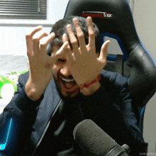 a man covering his face with his hands in front of a microphone with smhashley written in the corner
