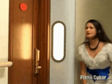 a woman in a white dress is standing in front of a door that says pisau ukur on it