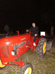 a man sits on a red tractor that says ' tractor ' on it
