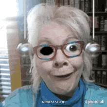a woman wearing glasses and a blue shirt is taking a selfie with the caption newest selfie