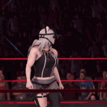 a woman wearing a cat mask and sunglasses stands in a wrestling ring with her hands in the air