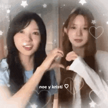 two young women are making a heart with their hands .