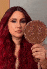 a woman with red hair is holding a peace sign hand mirror