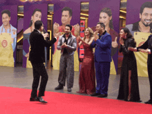 a group of people standing on a red carpet in front of a wall with a yellow apron that says mc on it