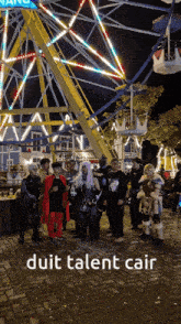 a group of people standing in front of a ferris wheel with the words duit talent cair below them