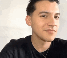 a close up of a man wearing a black shirt and a necklace .