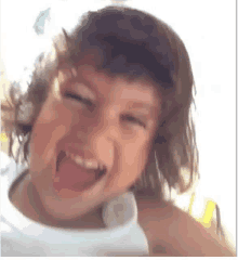 a young boy with long hair is making a funny face with his tongue out .