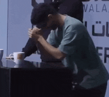 a man in a green shirt is arm wrestling another man in front of a wall that says vala