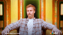 a man in a plaid shirt is sitting in a chair with nbc destination written on the bottom right