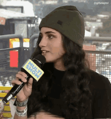 a woman wearing a green beanie is talking into a microphone that says multi show