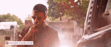 a man is smoking a cigarette in front of a no smoking sign