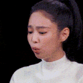 a close up of a woman 's face with a ponytail and a white shirt on .