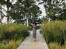 a woman stands on a wooden walkway taking a picture