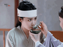 a woman in a white headband is being spoon fed