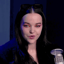 a woman wearing sunglasses is standing in front of a microphone with her mouth open