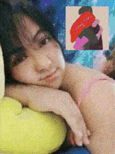 a woman in a pink bra is laying on a yellow pillow next to a painting of a woman hugging a man