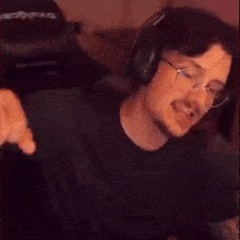 a man wearing glasses and headphones is sitting in front of a computer screen .