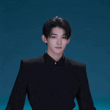 a young man in a black suit is pointing his finger at something
