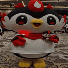 a penguin mascot with a red scarf around its neck holds a smaller penguin in its arms
