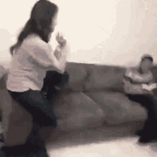 a woman is sitting on a couch while a man sits on a couch .