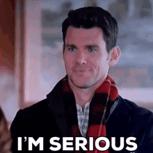 a man wearing a scarf and a jacket is making a serious face and saying i 'm serious .
