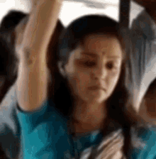 a woman in a blue shirt is holding onto a railing on a bus .