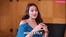a woman in a blue dress is sitting in a chair and says honestly .