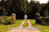 a man is running down a dirt road with the words `` going swimming '' written on the side .