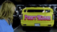 a woman is looking at a yellow pussy wagon truck