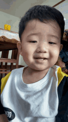a young boy wearing a white shirt that says den on it
